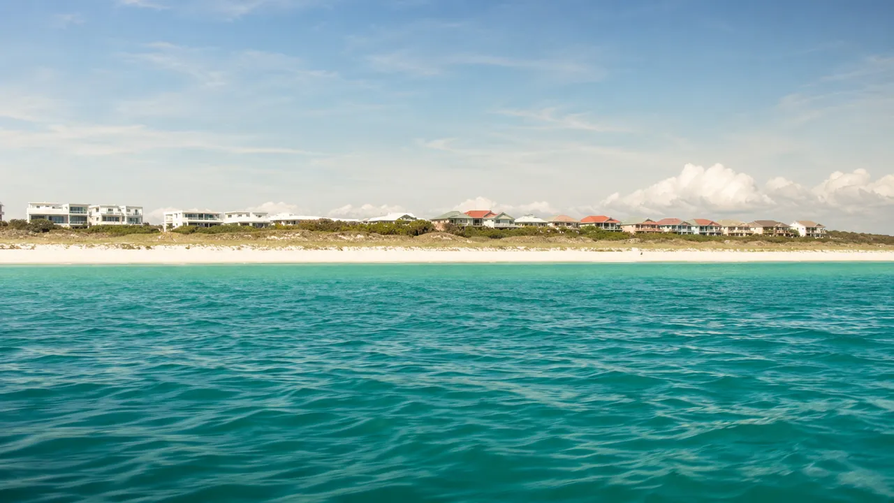 White dune line and rooftops along the length of the 30A coastline seen from a yacht offshore