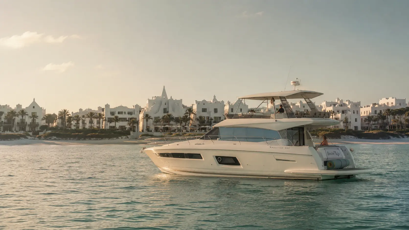 The Lovin' Life yacht anchored off Alys Beach, Florida, with the town's white architecture at sunset