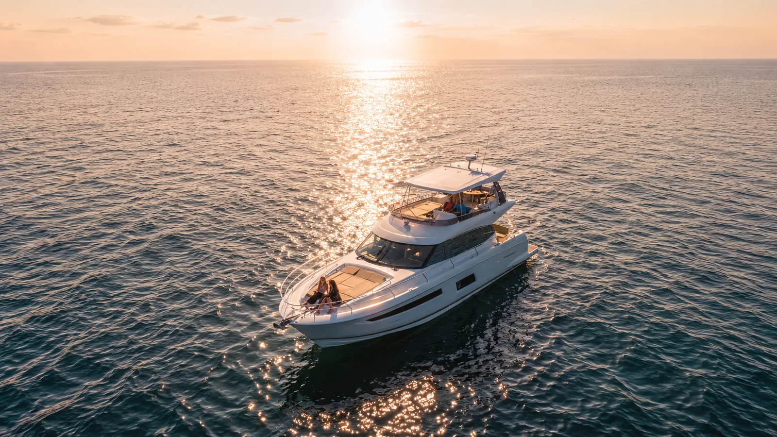 Aerial view of the Lovin' Life yacht cruising across open water toward the sunset over the Emerald Coast near Destin
