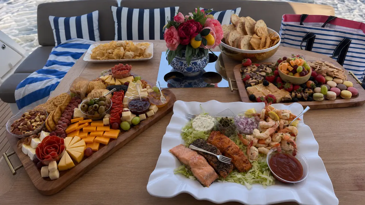 A large grazing table of charcuterie, seafood, and fruit aboard the Lovin' Life Destin yacht charter at sunset