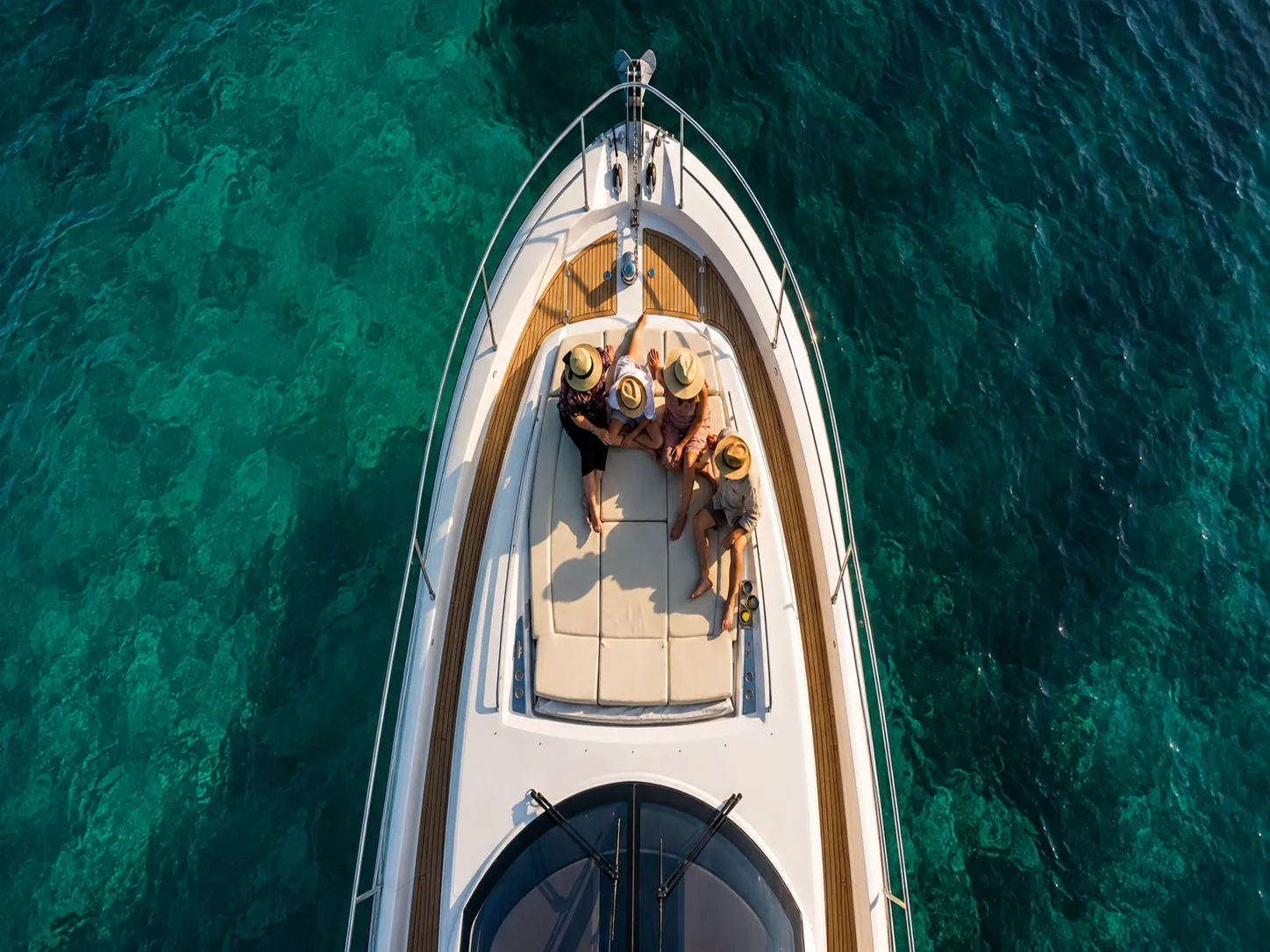 Aerial View of a Private 30A Charter on Empty Emerald Water Overhead aerial view of guests lying on the bow of a private yacht charter, alone on clear emerald water off the 30A coast