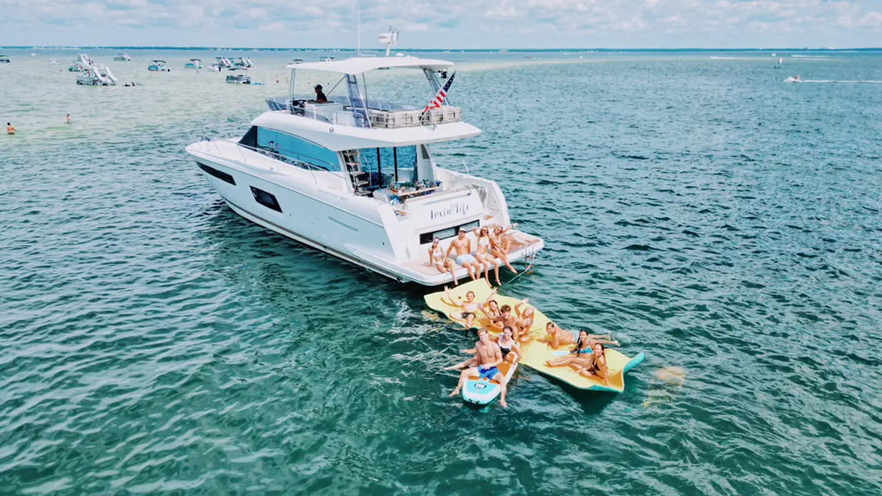 Guests paddleboarding beside the Lovin' Life yacht during a Destin charter on calm turquoise water at sunset