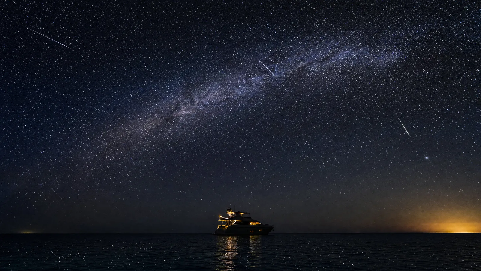 Perseid Meteor Shower and the Milky Way Over the Gulf of Mexico The Milky Way arcing over the Gulf of Mexico with Perseid meteors streaking across the star field, a single lit yacht anchored on the dark water below